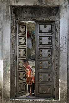 Boys Prints: Young little boy looking through a old wooden door, Moroni, Comoros, Africa
