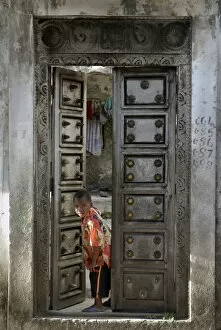 Images Dated 3rd August 2007: Young little boy looking through a old wooden door, Moroni, Comoros, Africa