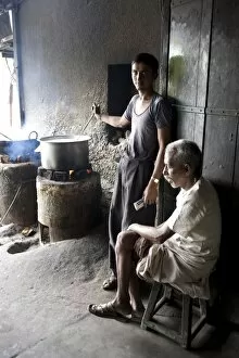 Images Dated 13th October 2009: Young man stirring milk for chai, with blind man sitting beside him, roadside chai stall