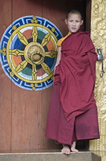 Young monk standing in the door of the Chimi Lhakhang monastery, Bhutan, Asia Young monk standing in the door of the Chimi Lhakhang monastery, Bhutan, Asia