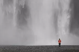 Young woman admiring the big waterfall of Skogarfoss, Iceland, Polar Regions