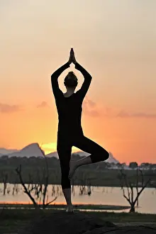 Strength Prints: Young woman practising yoga posture by the Senanayake Samudraya Lake at sunset
