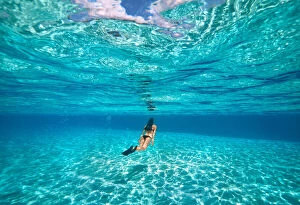 South Pacific Gallery: A young woman swimming underwater in clear blue shallow lagoon with a sandy bottom