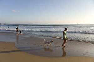 A young woman walks her dog at Arrifana beach