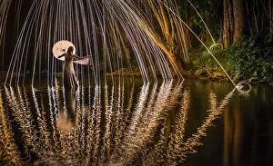 Females Prints: A young woman in a white dress standing in a river at night extends her hand to catch a